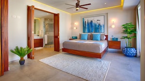 A modern bedroom with a large bed, a ceiling fan, a painting, and a potted plant. - Designer 2BR w/ Balcony & Pool in Romantic Zone (Puerto Vallarta)