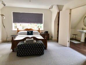 Quarto com cama, mesa de cabeceira, luminária e vista para uma janela.