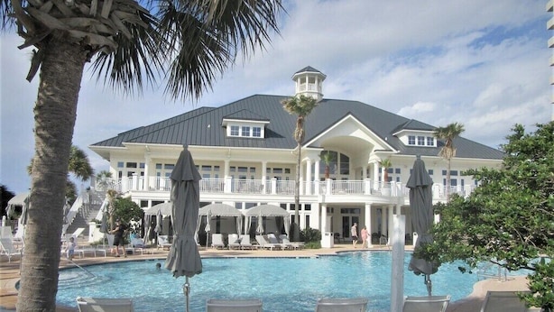 A large resort with a swimming pool, lounge chairs, and umbrellas. - Beach Club Ground Floor! Right on the beach - Pools- WIFI (Gulf Shores)