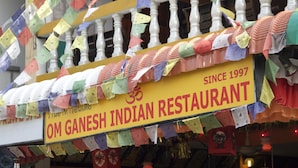 A restaurant sign with colorful prayer flags and a yellow banner stating "OM GANESH INDIAN RESTAURANT SINCE 1997". - Om Ganesh Hostel - Adults Only (Ko Pha-ngan)