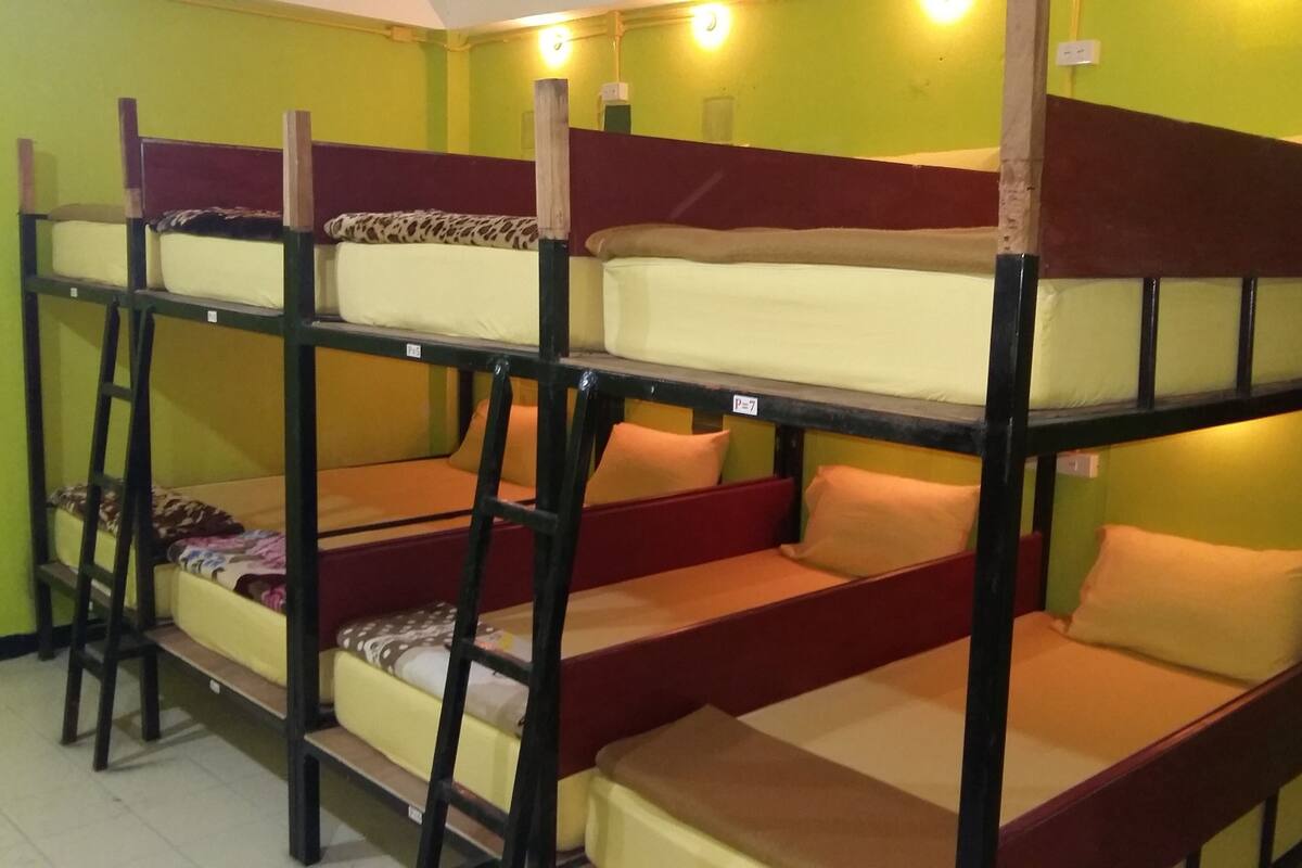Une chambre avec des lits superposés à trois niveaux, chaque lit étant équipé d’un matelas et d’oreillers.