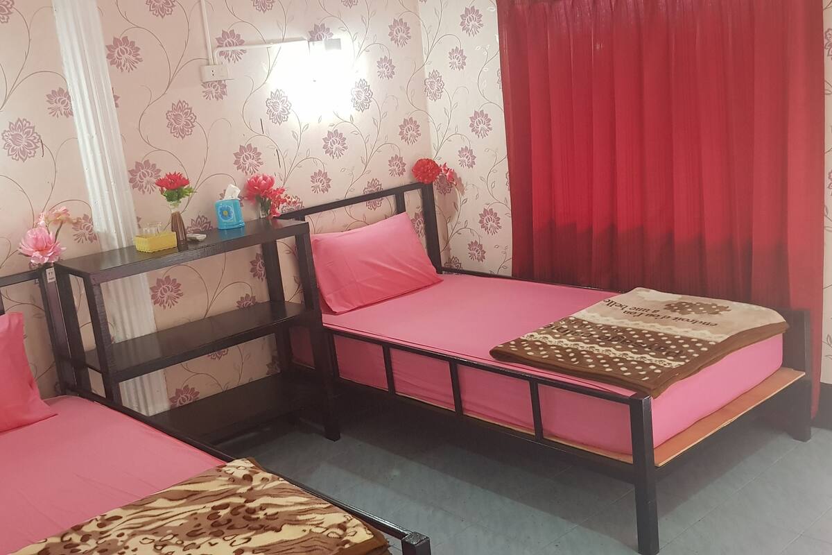 Une chambre à coucher avec un lit, une table de chevet, un miroir et une fenêtre avec des rideaux.