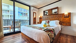 Ein Hotelzimmer mit einem großen Bett, einem hölzernen Kopfteil, einem Balkon mit einem Stuhl und Blick auf ein Gebäude mit Balkonen.