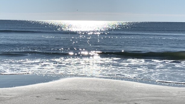 A beach with a clear sky and sunlight reflecting off the water. - Happy Place Gated ResortBldg.1,First floor, pool, deli/gift shop, bar (Hilton Head)