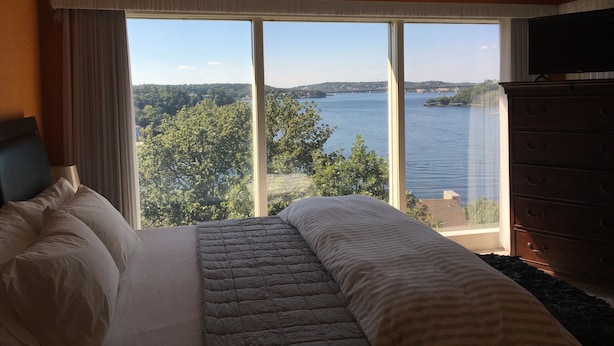 Une chambre avec une grande fenêtre donnant sur un lac et un pont.