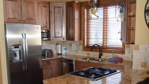 Una cocina con gabinetes de madera, electrodomésticos de acero inoxidable, encimeras de granito y una estufa a gas.