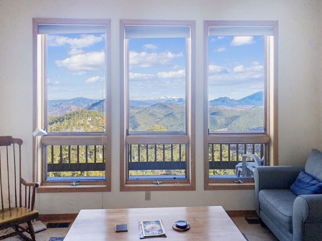 A room with three large windows offering a mountain view.