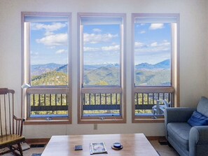 Una habitación con tres ventanas amplias que dan a vistas de la montaña.