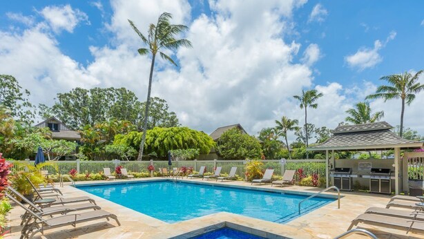 A rectangular swimming pool with a small hot tub section, surrounded by lounge chairs and a covered seating area. -  Fresh & Clean, Air Conditioned Second Floor Condo in Princeville  (Princeville)