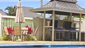 A poolside area with a barbecue setup, lounge chairs, and a covered seating area. -  Fresh & Clean, Air Conditioned Second Floor Condo in Princeville  (Princeville)