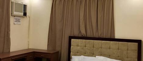 A hotel room with a bed, a desk, and a ceiling light.