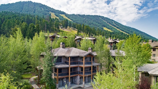 A multi-story lodge with a stone facade and balconies, surrounded by lush greenery and mountains in the background. - Outpost: Love Ridge 252 - Spacious, Air Conditioned (Jackson)