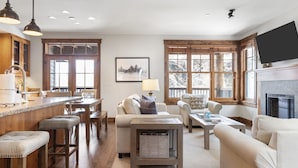 A spacious living room with a large window, a fireplace, and a kitchen area with wooden cabinets and bar stools. - Outpost: Love Ridge 252 - Spacious, Air Conditioned (Jackson)