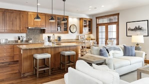 A modern kitchen with wooden cabinets, a granite countertop, and a central island with stools. - Outpost: Love Ridge 252 - Spacious, Air Conditioned (Jackson)