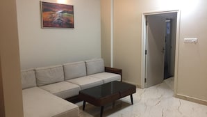 A living room with a sofa, a coffee table, and a painting on the wall. - Lali Petals (Madikeri)