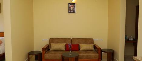 A living room with a sofa, two side tables, a wall-mounted light, and a framed picture.