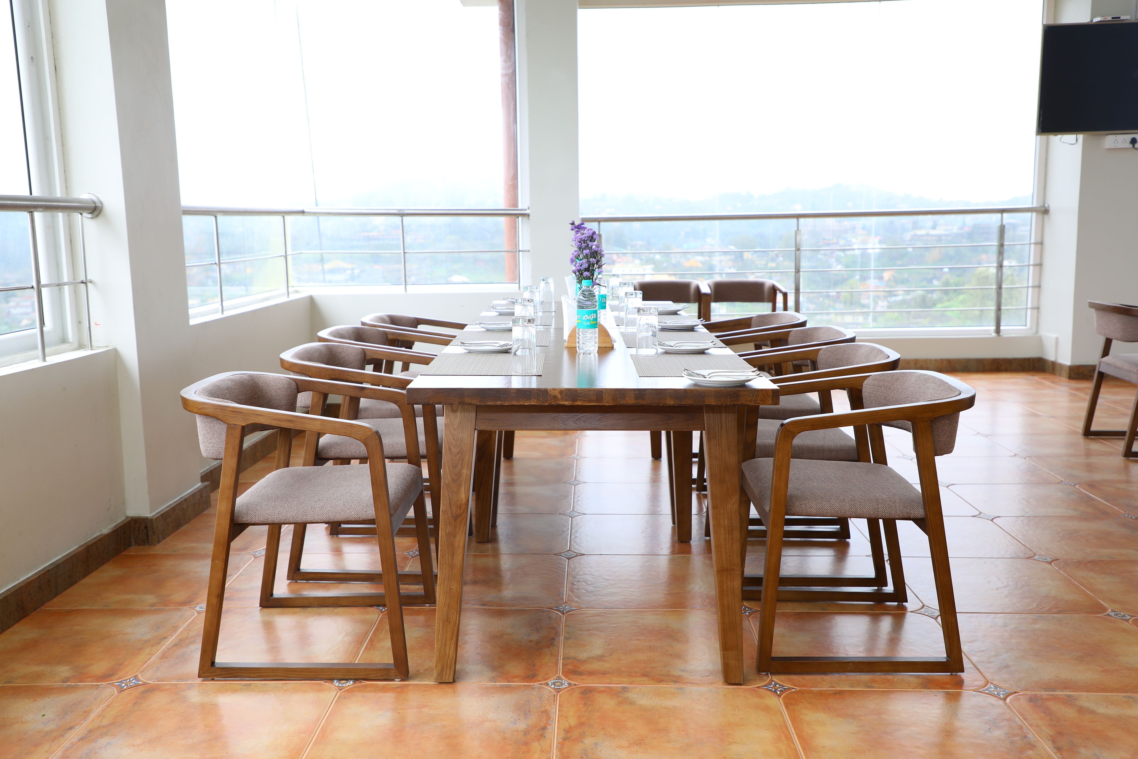 A conference room with a long table and chairs, large windows with a city view, and a flat-screen TV on the wall.