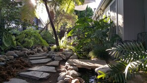 A garden with a stone pathway, rocks, and various plants. - SERENITY IN CDM: Private Cottage & Gardens on XL Lot (Corona del Mar)