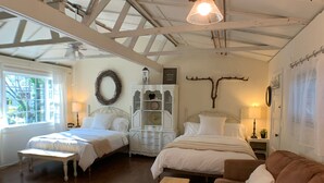 A spacious room with a high ceiling, wooden beams, a large bed, a sofa, and a bench.