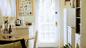 A cozy living room with a brown sofa, a coffee table, and a door leading to a kitchen.