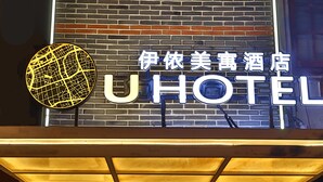 La entrada a UHOTEL con un cartel llamativo, un arco de ladrillo y una vista despejada del interior.