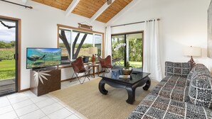 Un vaste espace de vie doté d’un ventilateur de plafond, d’un grand téléviseur à écran plat, d’un canapé et d’une table basse.