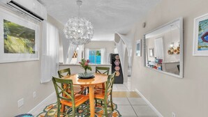 Un coin repas avec une table ronde, des chaises, un lustre décoratif et un tapis coloré.