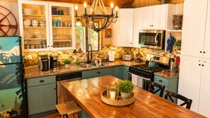 A kitchen with a wooden table, cabinets, a stove, and a refrigerator. - Private Hot Tub in the Pines in North Lake Tahoe (Carnelian Bay)