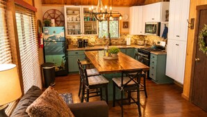 A cozy kitchen with wooden cabinets, a central island, and a dining area with a sofa and chairs. - Private Hot Tub in the Pines in North Lake Tahoe (Carnelian Bay)