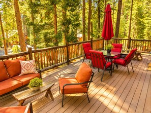 Una terraza de madera con mobiliario exterior, una mesa y sillas.
