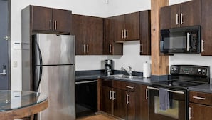 Una cocina moderna con armarios de madera oscura, electrodomésticos de acero inoxidable y una mesa de vidrio.