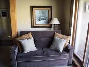 Relax in this inviting living room with a sofa, framed artwork, and a floor lamp.