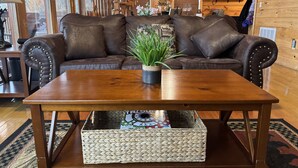 Ein gemütliches Wohnzimmer mit einem braunen Ledersofa, einem Holztisch und einem gewebten Korb.