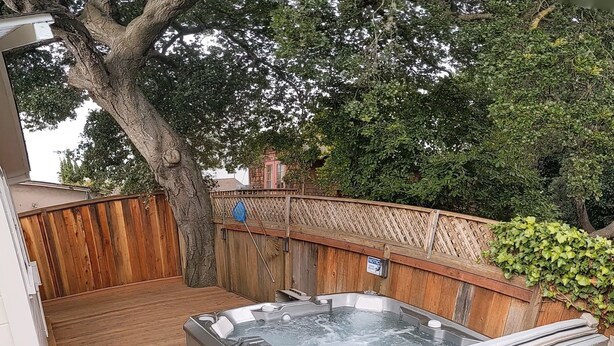 A hot tub in a backyard with a wooden deck, surrounded by a wooden fence and trees. - Cozy Private Beach Bungalow, New Hot Tub,  1 Dog ok, 3 short Blocks To Beach. (Santa Cruz)