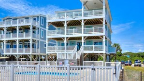 A multi-story beachfront hotel with balconies, a pool, and a beach view.