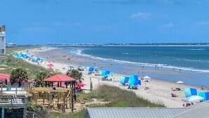 A beach with umbrellas, beach chairs, and a boardwalk.