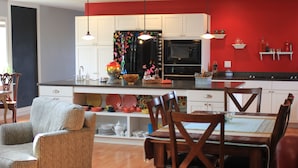 A modern kitchen with white cabinets, a black refrigerator, and a dining area with wooden chairs and a table. - Stay in downtown Three Oaks overlooking the main street!  (Three Oaks)