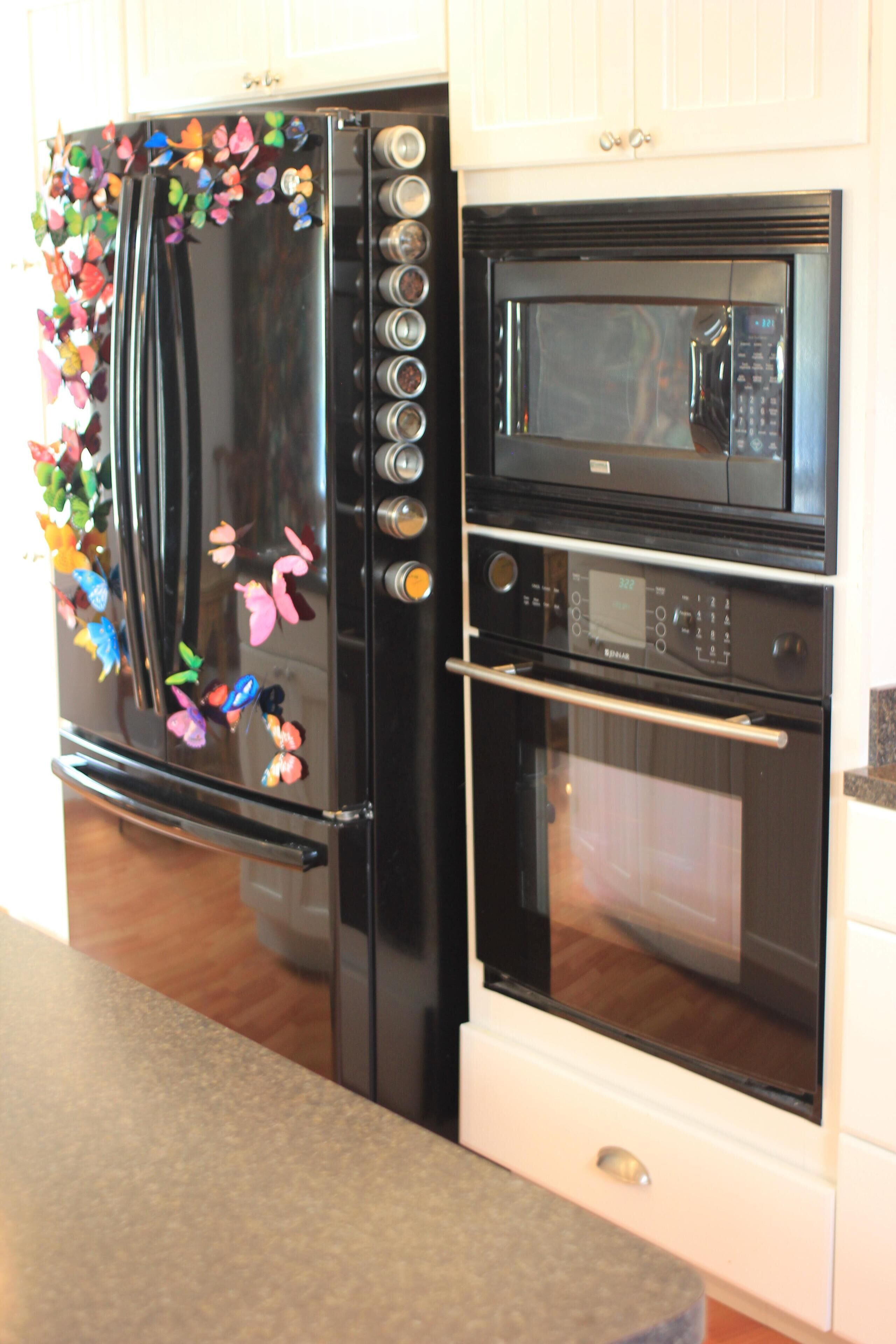 A kitchen with a black refrigerator, microwave, and oven.