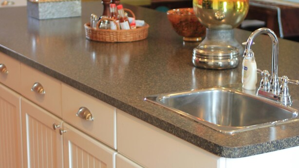 A kitchen with a granite countertop, stainless steel sink, and white cabinetry. - Stay in downtown Three Oaks overlooking the main street!  (Three Oaks)