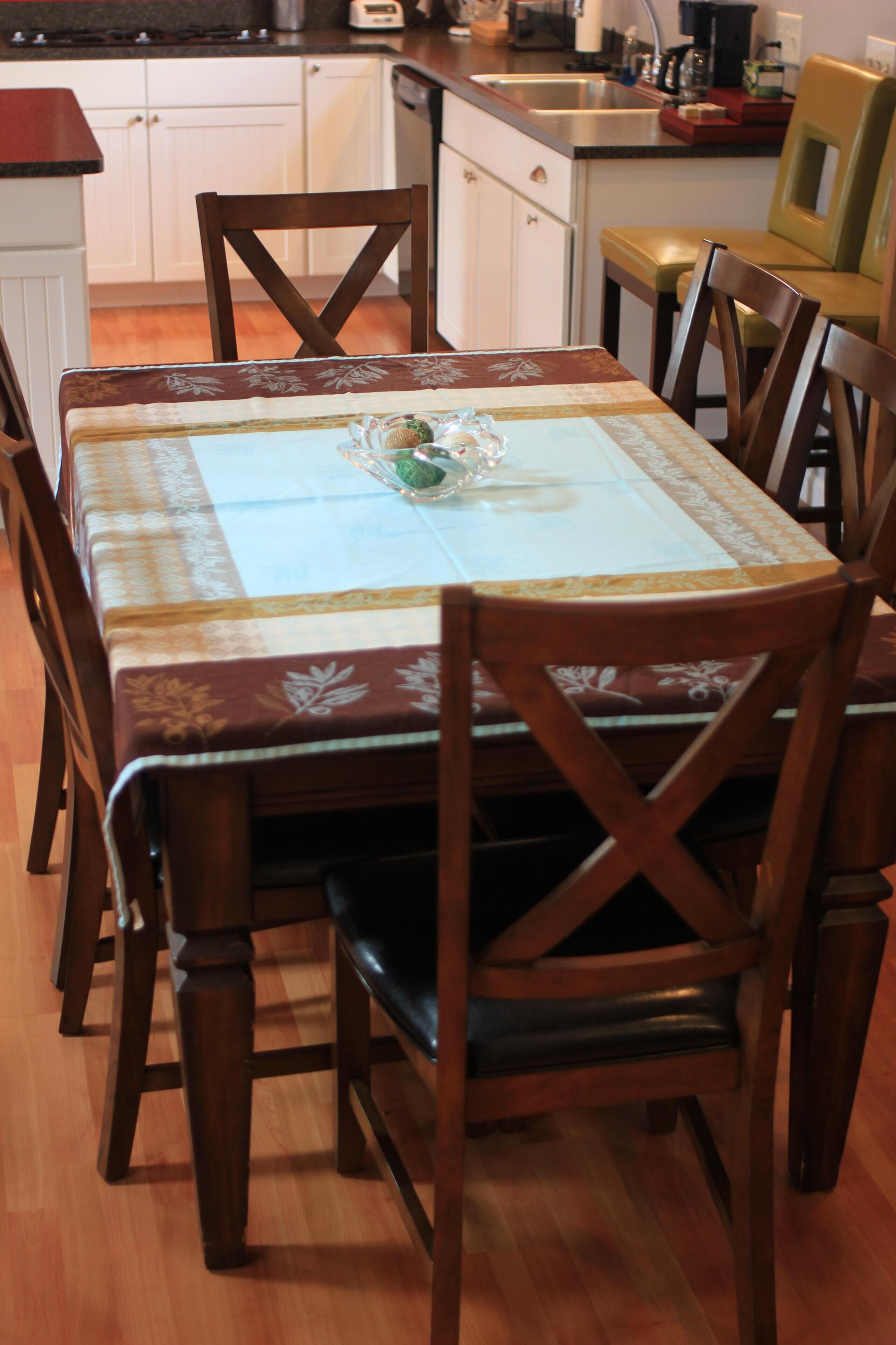 A dining table with a floral tablecloth, surrounded by wooden chairs.