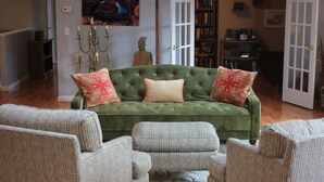 A green sofa with two red and one beige cushion, surrounded by patterned armchairs, in a room with a wooden floor and a white rug. - Stay in downtown Three Oaks overlooking the main street!  (Three Oaks)