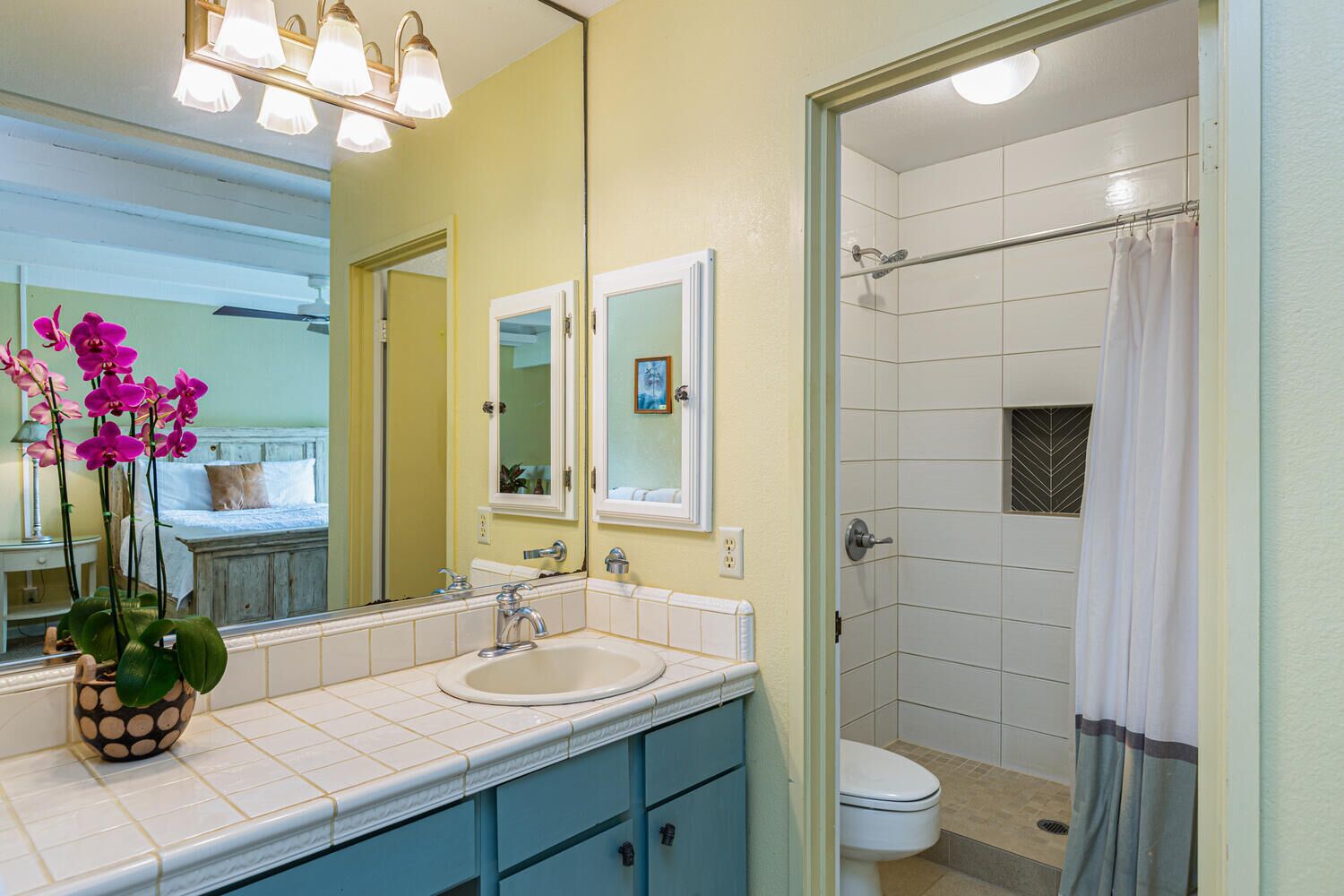 A bathroom with a double sink, a shower, and a toilet.