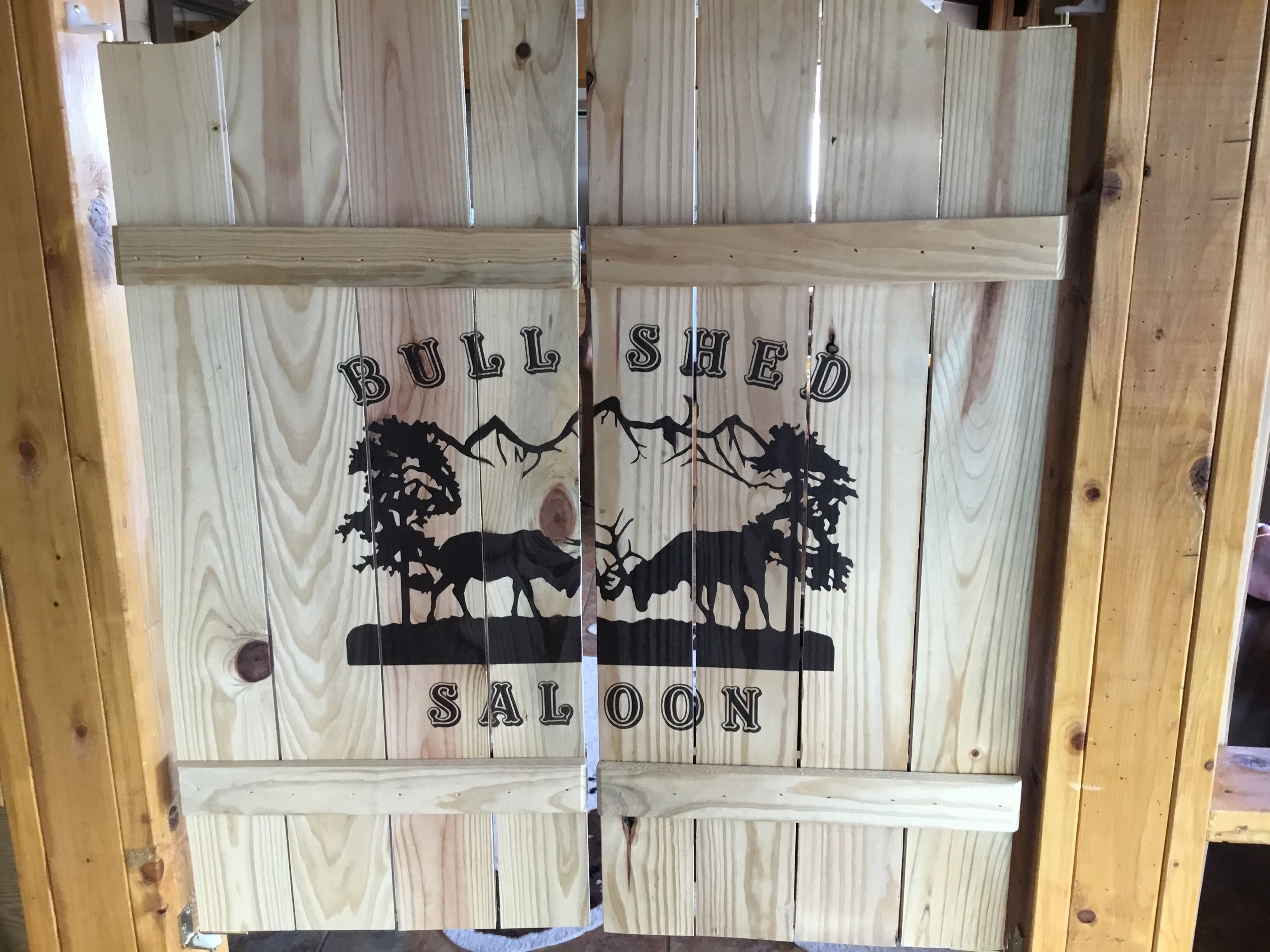 A wooden sign with the text "BULLSHED SALOON" and a graphic of a bull and trees.