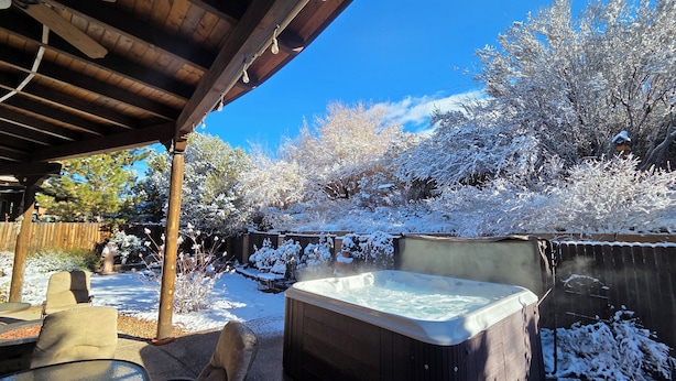 Un espacio al aire libre cubierto con un jacuzzi, sillas de madera y una valla de madera.