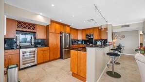 A modern kitchen with wooden cabinets, stainless steel appliances, and a central island with bar stools.