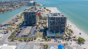 A coastal hotel with multiple buildings, a parking lot, and a beach.