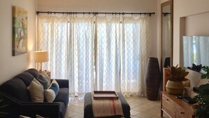 Uma sala de estar com sofá, pufê e televisão sobre um móvel de madeira.