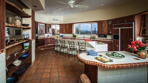 A spacious kitchen with a central island, bar stools, and a view of the outdoors. - Hacienda near Ritz Carlton 360 views on 5 ac, all bdrms ensuite bathrms (Marana)