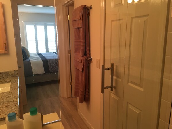Una habitación de hotel con cama, baño con ducha y un toallero.