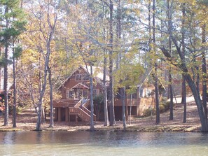 A cabin with a wooden deck and a staircase leading to a second level.